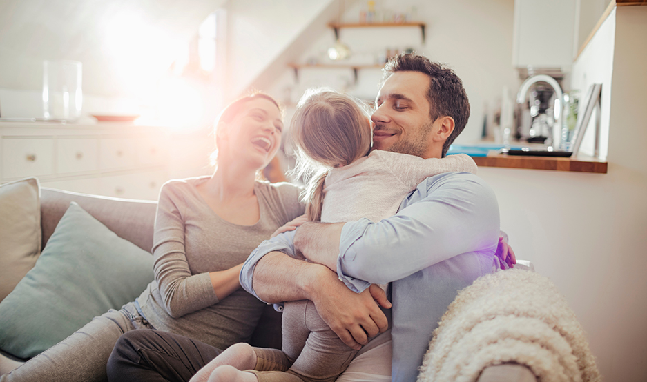 Happy young family relaxing on the couch at home